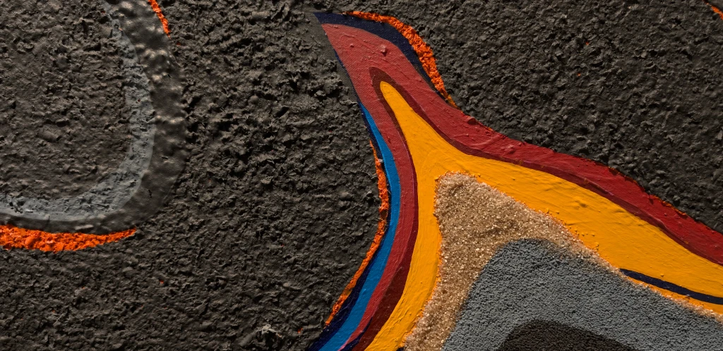 A close up detail photo of the Rita Deanin Abbey work 'Magma, 1975.' This photo emphasizes the orange and red saturated line that cuts through the center of the composition. The top half of the work has a rough texture coated in black paint. The light reflecting off the work emphasizes the textured composition.
