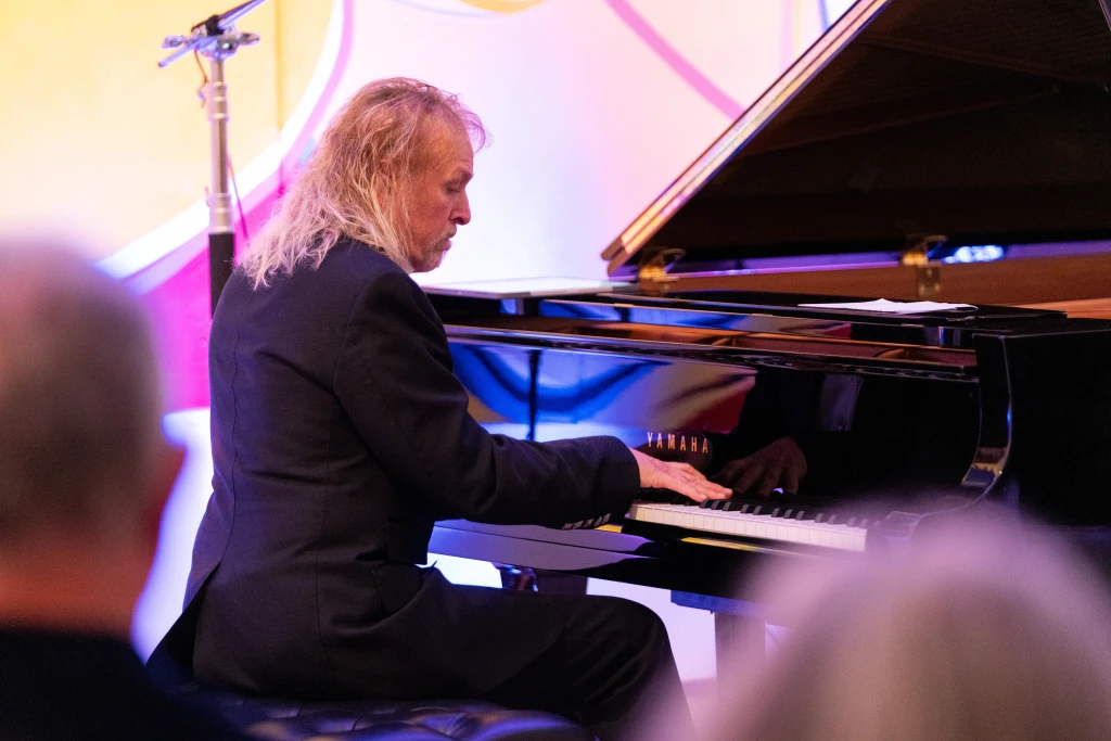 Philip Fortunbery playing piano in front of an audience, sitting with the piano to the right of frame